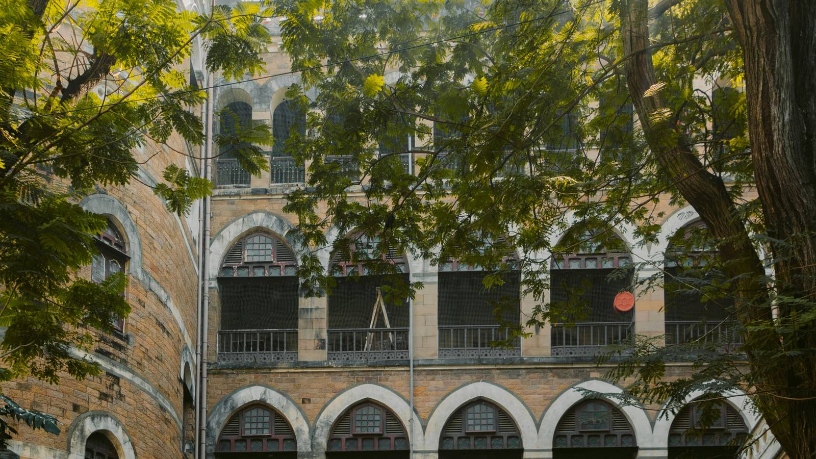 A pre-war arcaded building in Mumbai, seen through trees